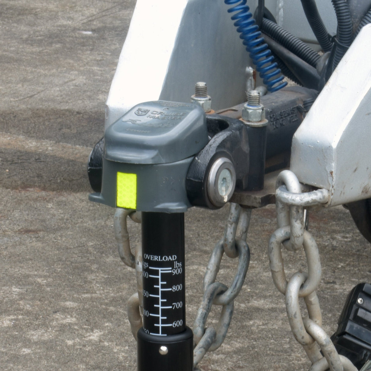 Towing hitch with chain on a trailer attached to a Tow Ball Weight Scale with a DO35 Hitch on a concrete surface.
